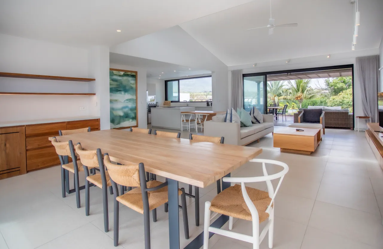Salle à manger spacieuse avec table en bois et chaises confortables.  
Lumière naturelle abondante grâce aux grandes fenêtres sur le jardin.  
Mobilier sobre et fonctionnel créant une atmosphère conviviale.  
Accès direct à l’espace de vie depuis la salle à manger.  
Éléments décoratifs discrets ajoutent une touche contemporaine à l’ensemble.
