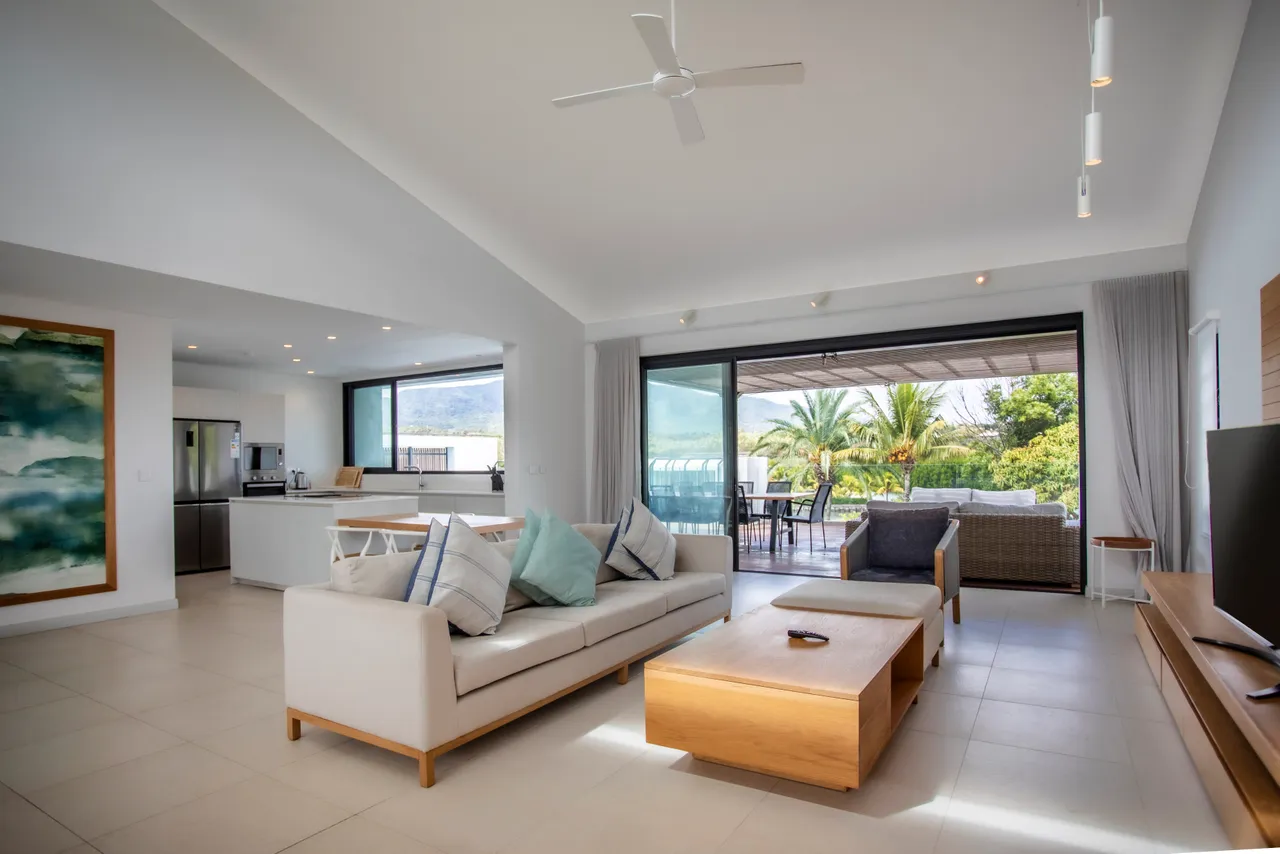 Lumière naturelle pénétrant par de grandes baies vitrées offrant une vue sur l'extérieur.  
Espace de vie ouvert intégrant un coin salon et une cuisine moderne.  
Mobilier clair et sobre créant une atmosphère fonctionnelle et contemporaine.  
Plafond haut accentuant la sensation d'espace et de luminosité.  
Accès direct à la terrasse pour prolonger