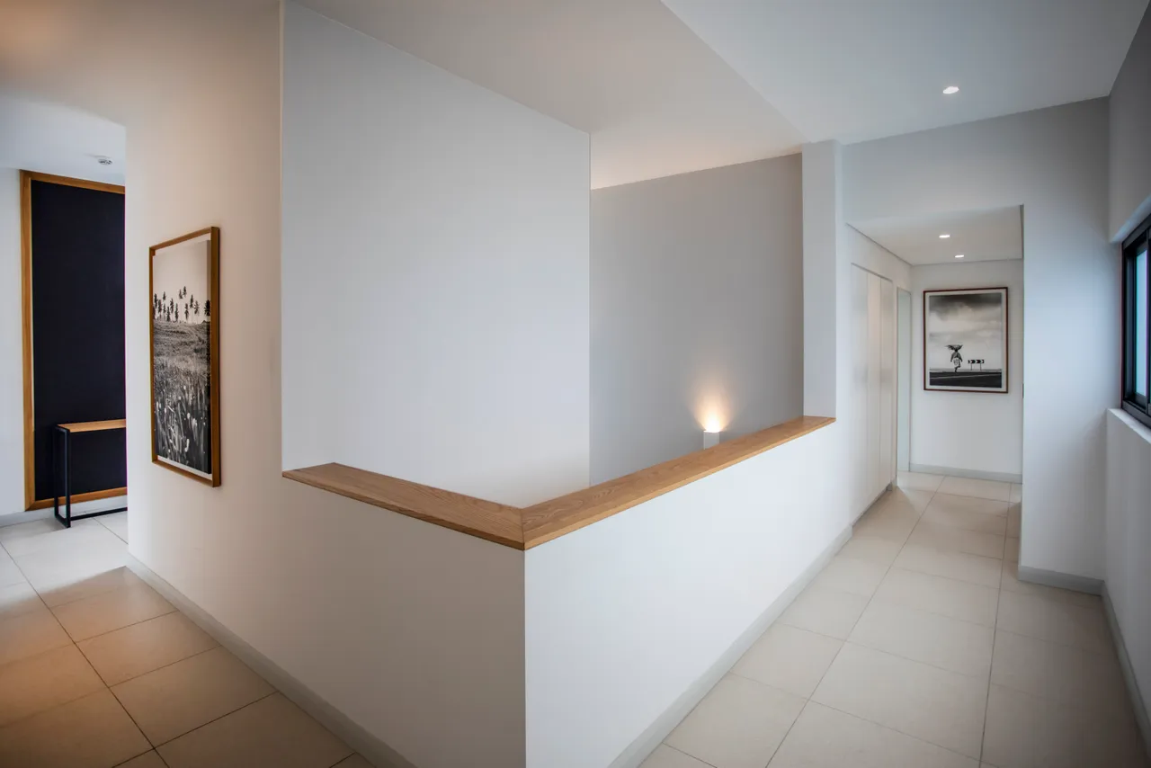 Couloir lumineux avec murs blancs et finition en bois.  
Accès direct aux différentes pièces du penthouse.  
Éclairage intégré soulignant l'espace et les lignes épurées.  
Sol carrelé apportant une touche moderne à l'agencement.  
Détails architecturaux simples créant une ambiance sereine.
