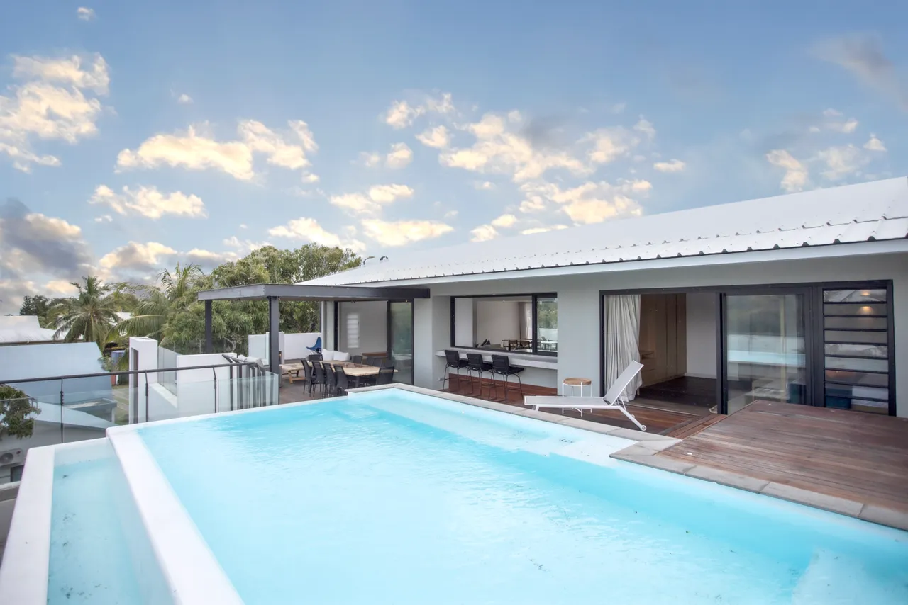 Espace extérieur avec piscine privée offrant une vue dégagée.  
Terrasse en bois équipée de chaises longues pour la détente.  
Coin repas extérieur idéal pour profiter des repas au soleil.  
Végétation environnante créant une atmosphère naturelle au bord de la piscine.  
Mobilier contemporain sur la terrasse pour un confort appréciable.