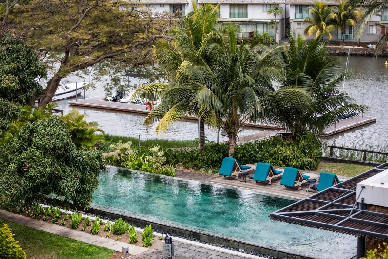 Terrasse en bois équipée de chaises longues pour des moments de détente.  
Végétation environnante offrant une atmosphère naturelle et apaisante.  
Piscine privée visible depuis la terrasse, ajoutant un élément d'eau.  
Coin repas extérieur pour profiter des repas en plein air.  
Vue sur l'environnement naturel depuis l'espace extérieur.