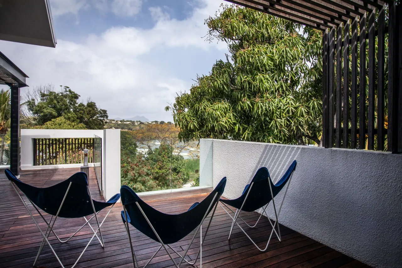 Terrasse en bois avec chaises inclinables pour profiter de la vue.  
Végétation environnante ajoutant une touche naturelle à l'espace extérieur.  
Espace extérieur spacieux permettant de se détendre au soleil.  
Accès direct à la piscine depuis la terrasse, facilitant la baignade.  
Ambiance tranquille créée par la disposition des chaises et la végétation.