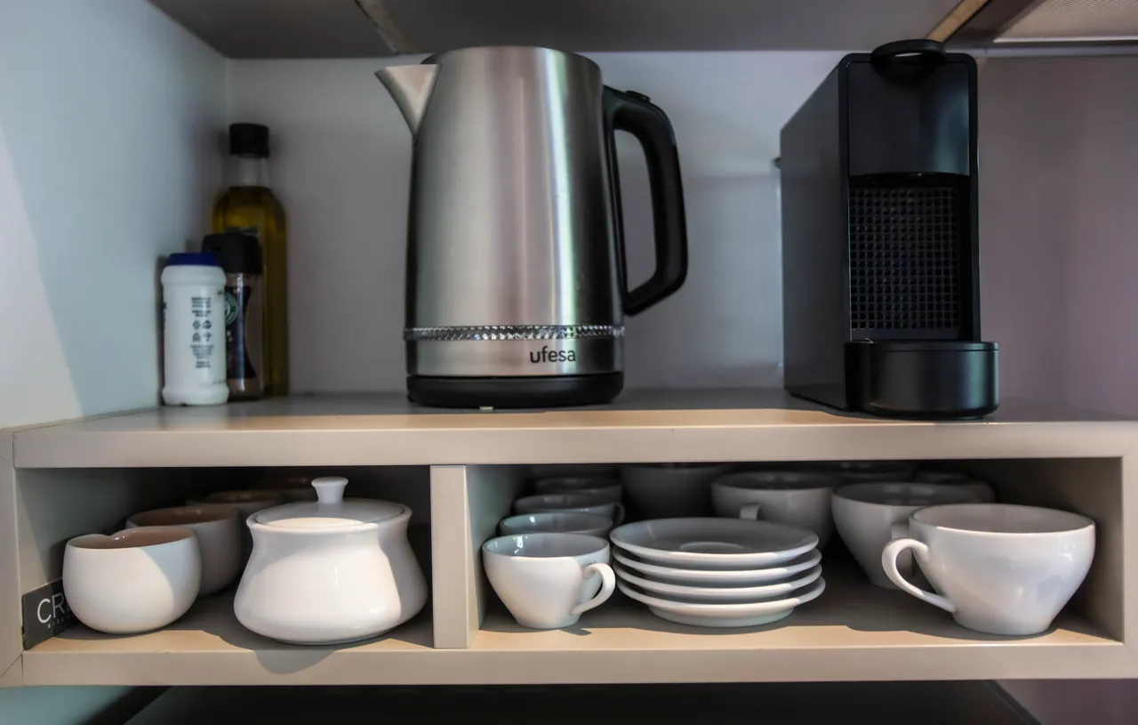 Éléments en acier inoxydable et vaisselle en céramique dans la cuisine.  
Rangement organisé avec étagères et tiroirs pour un accès facile.  
Électroménagers modernes intégrés pour une utilisation efficace.  
Surface de travail claire permettant une préparation aisée des repas.  
Accessoires de cuisine en harmonie avec le style contemporain.