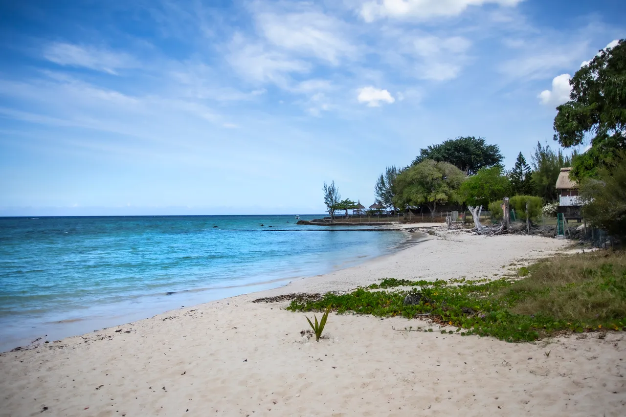 Plage de sable fin menant à des eaux turquoise.  
Végétation côtière ajoutant une touche naturelle au paysage.  
Ciel dégagé créant une atmosphère lumineuse et aérée.  
Terrains en pente douce conjuguant simplicité et beauté naturelle.  
Ambiance paisible avec le bruit des vagues au loin.