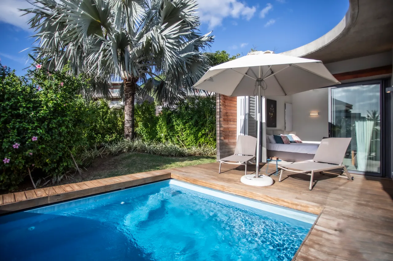 Espace extérieur avec piscine et chaises longues. Ombre apportée par un parasol.