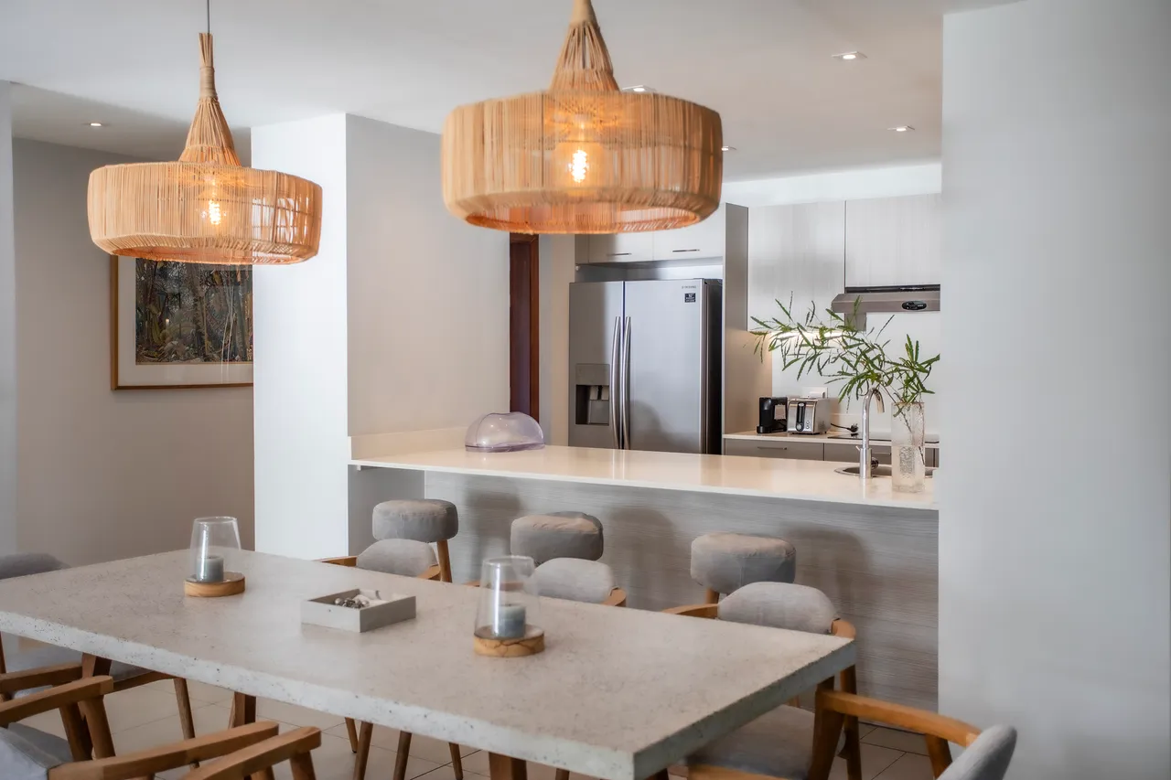Espace dining avec table en pierre et chaises en bois. Éclairage en osier pour une ambiance douce.