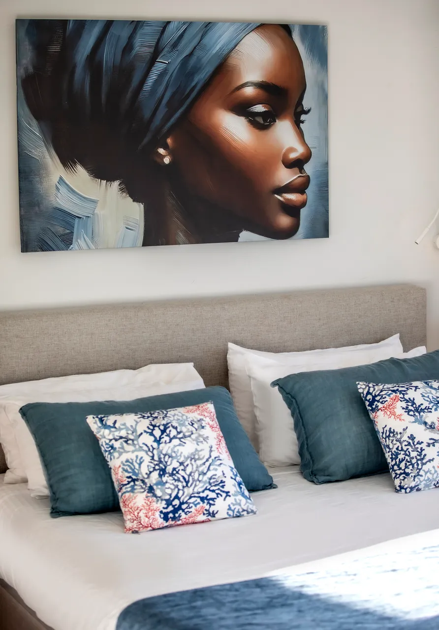 Literie blanche avec coussins décoratifs aux motifs marins. Tête de lit en tissu beige.