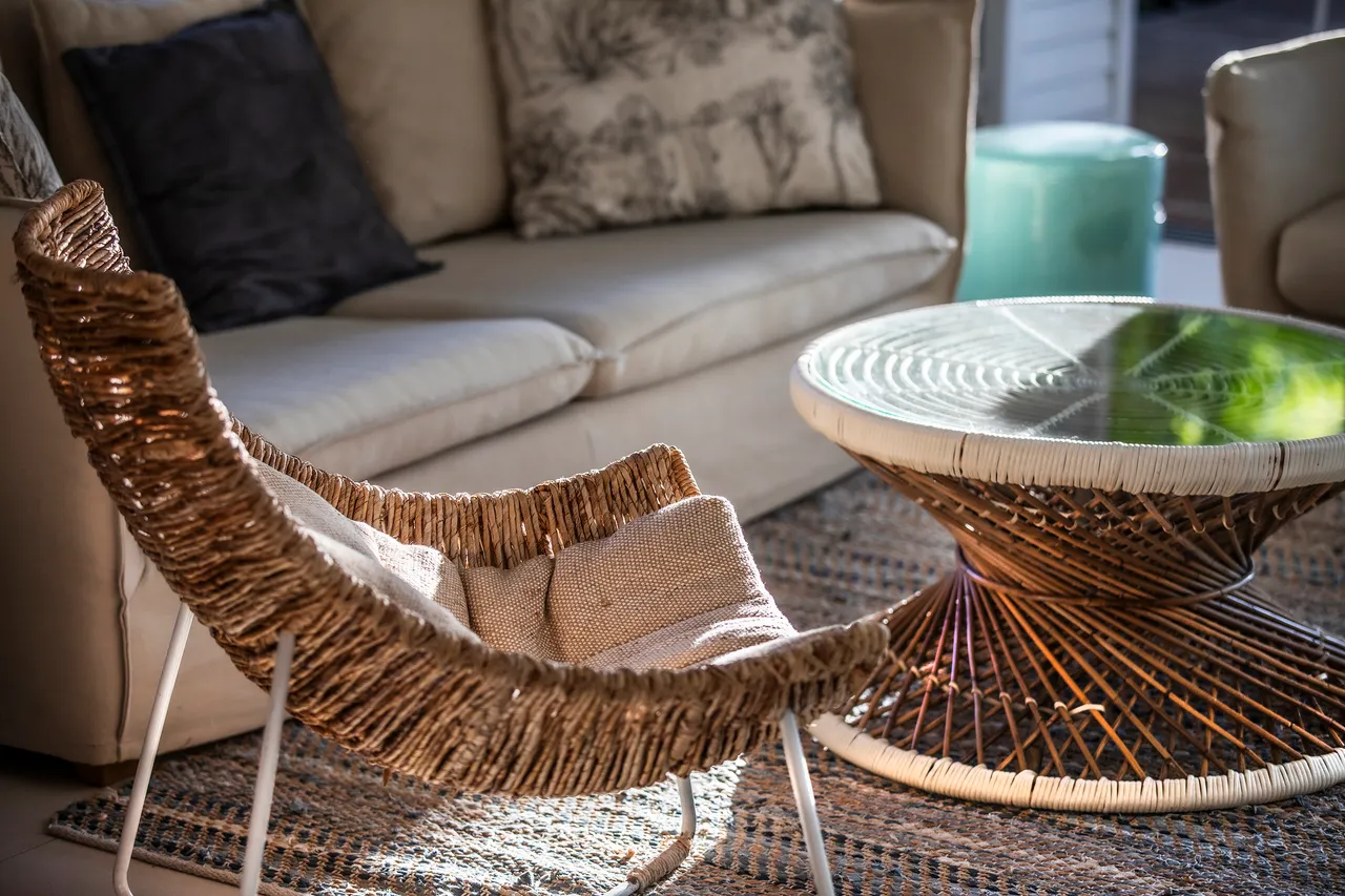 Salon avec fauteuil tressé en rotin et table basse en osier. Espace lumineux et chaleureux.