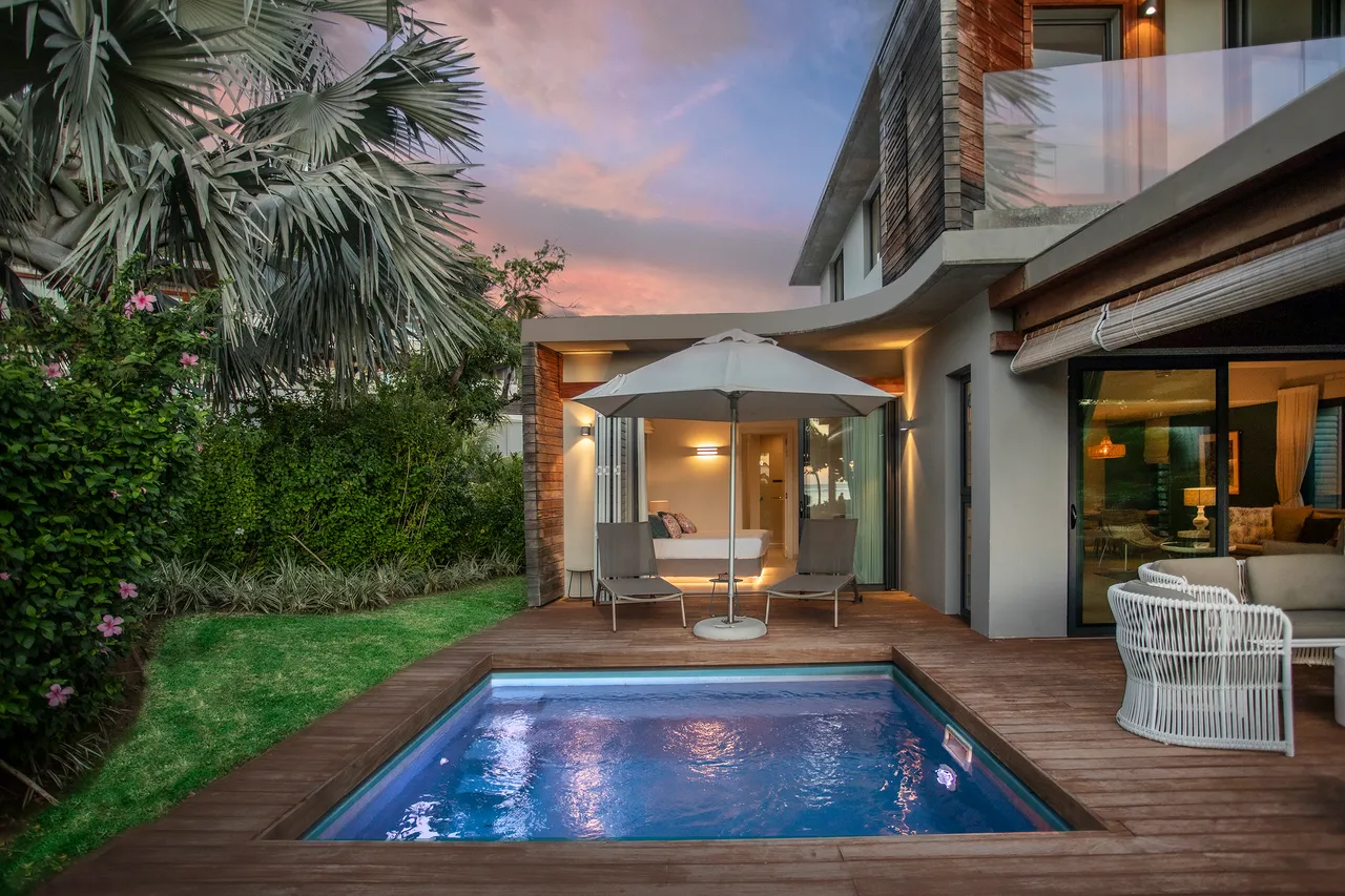 Espace extérieur avec piscine privée et coin salon ombragé. Végétation tropicale entourant l'ensemble.