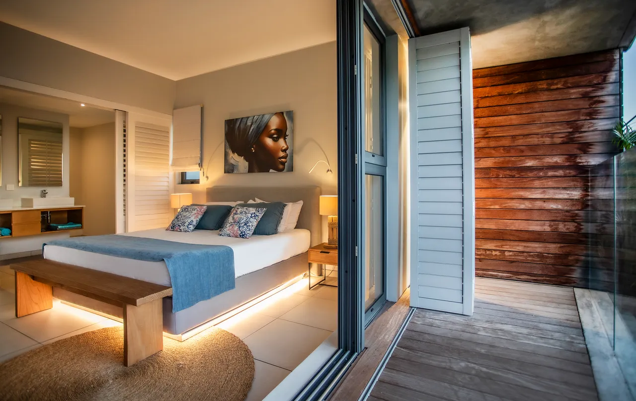 Chambre avec accès direct à un balcon en bois. Grande fenêtre laissant entrer la lumière naturelle.