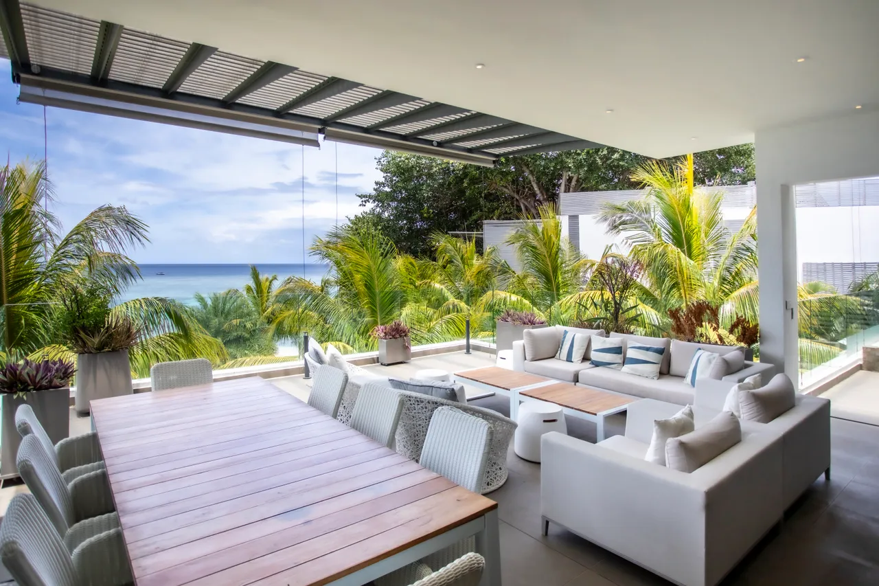 Espace repas. Grande table en bois entourée de chaises confortables, offrant une vue sur la mer.