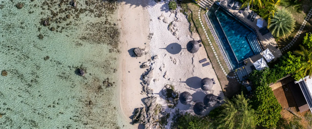 Vue sur la plage et la piscine depuis le penthouse. Espace de détente ombragé.