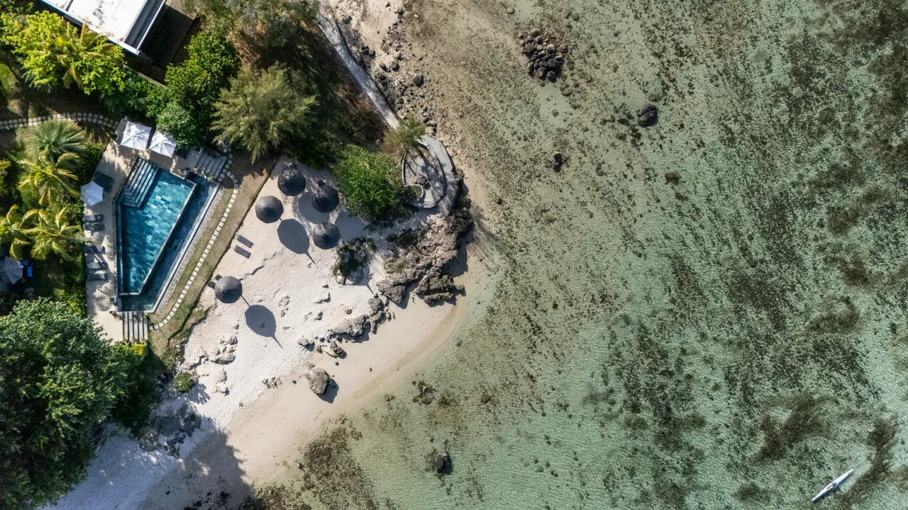Vue sur la plage et la piscine depuis le penthouse, avec parasols.