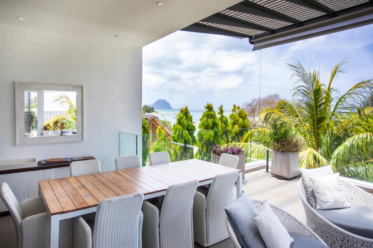 Espace repas avec grande table en bois et chaises confortables. Vue sur la mer.