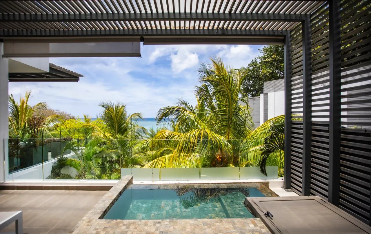 Espace extérieur avec piscine privée et vue sur la mer. Environnement verdoyant tout autour.