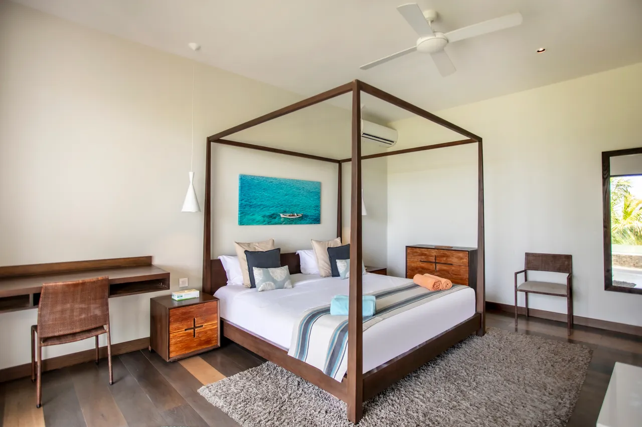 Chambre avec lit à baldaquin et bureau en bois. Sol en parquet clair.