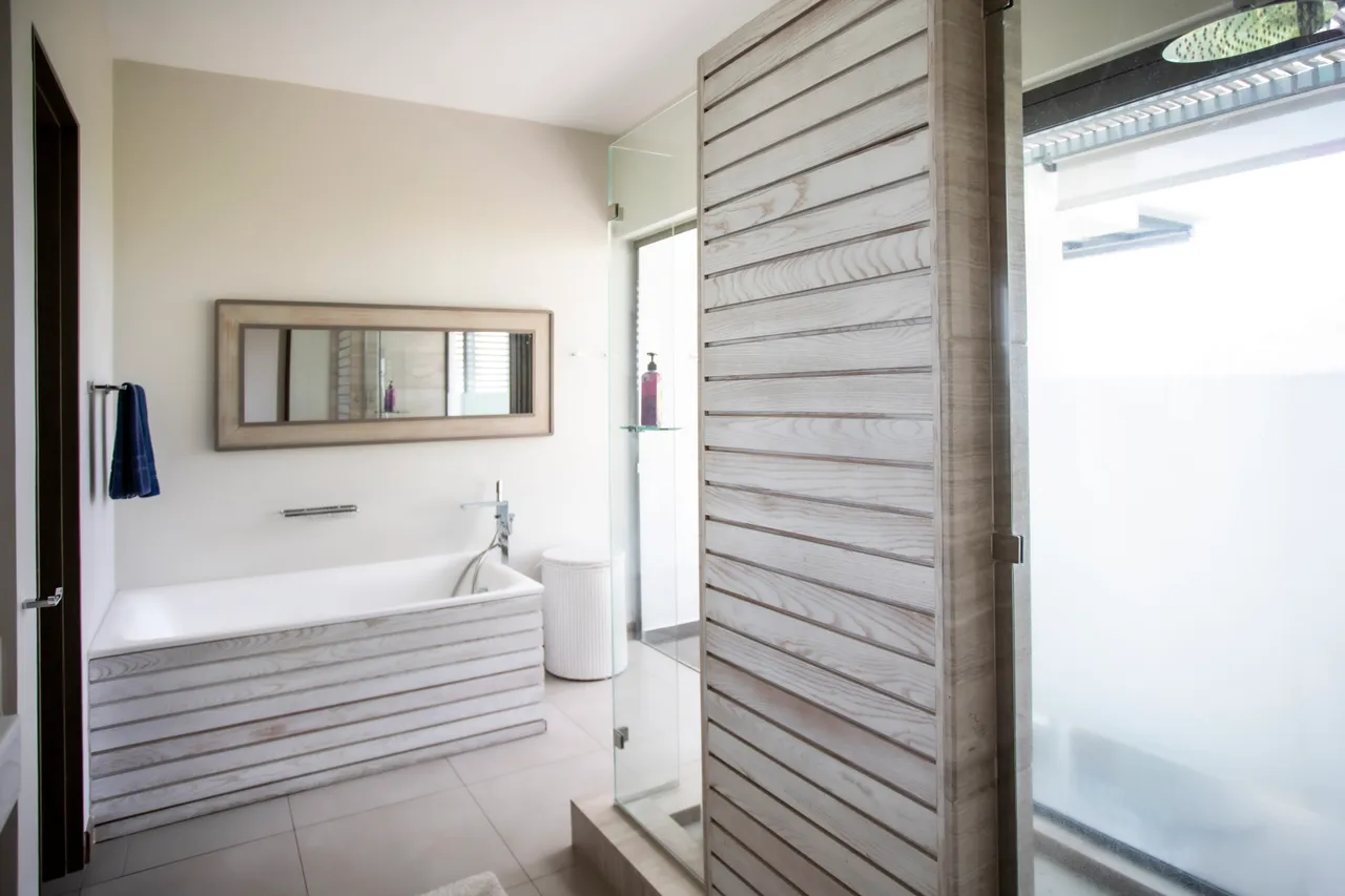 Sombre bois clair et carrelage beige dans la salle de bain. Douche séparée avec paroi en verre.