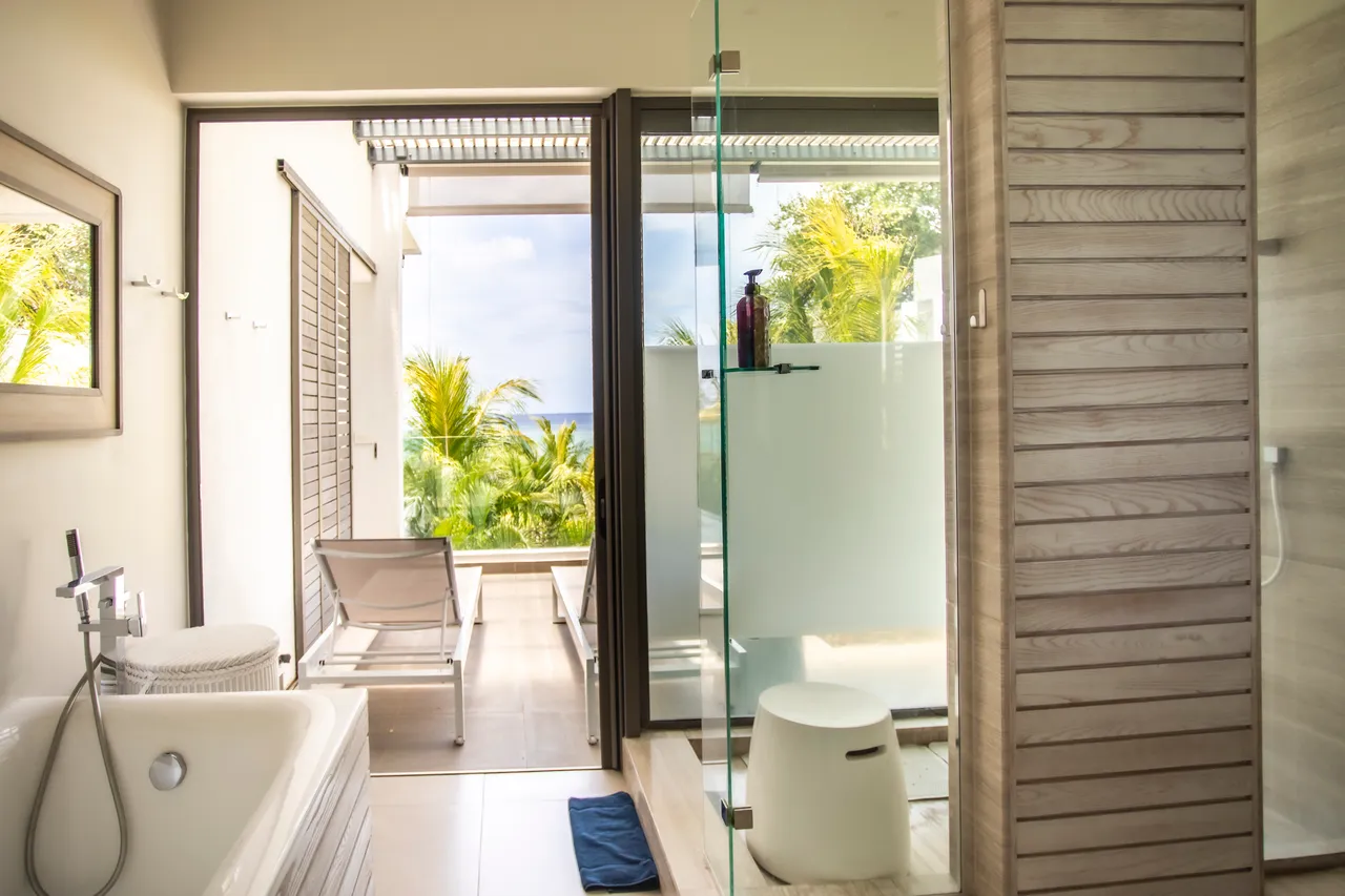 Salle de bain avec douche vitrée et accès à un balcon privé. Vue sur le jardin.