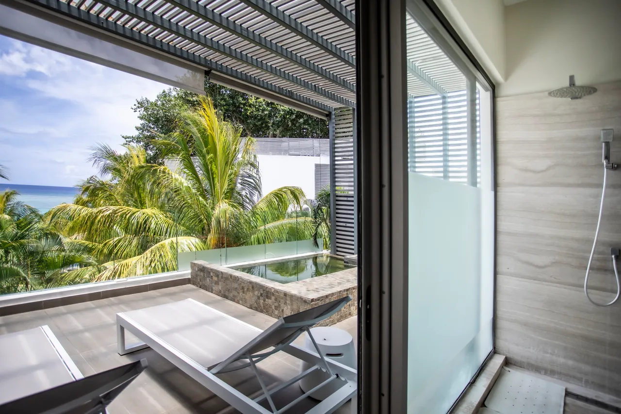 Sol en carrelage moderne et douche extérieure. Chaises longues avec vue sur la mer.