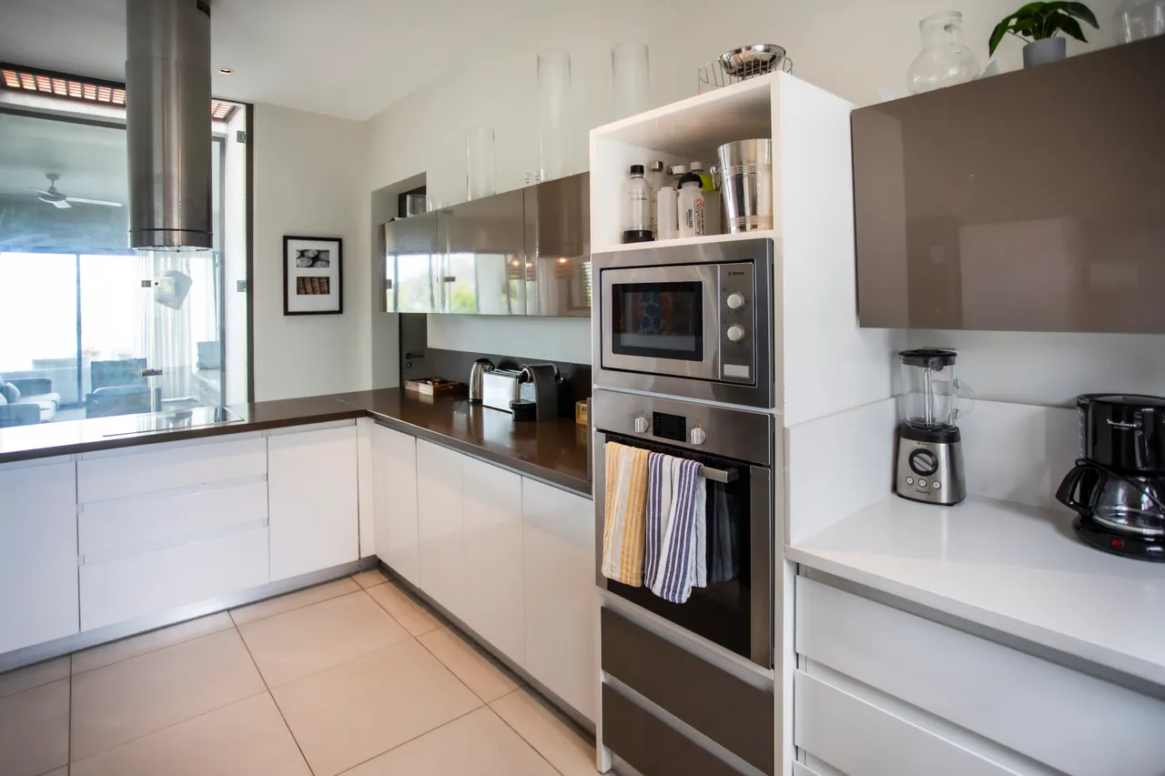 Cuisine spacieuse avec électroménagers intégrés et surfaces en gloss. Luminosité naturelle grâce à de grandes fenêtres.