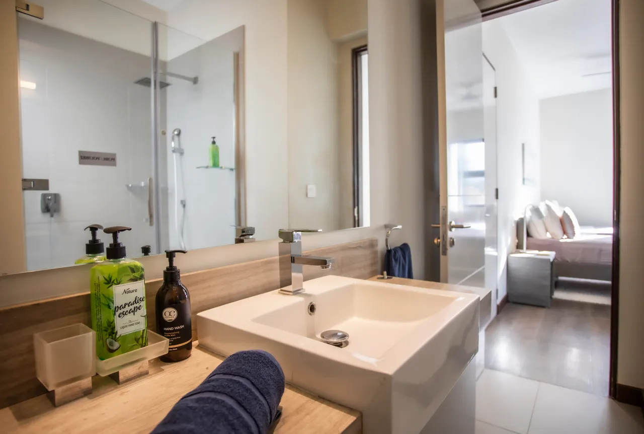 Salle de bain lumineuse avec un lavabo simple et douche séparée. Rangement pratique et accessoires modernes.