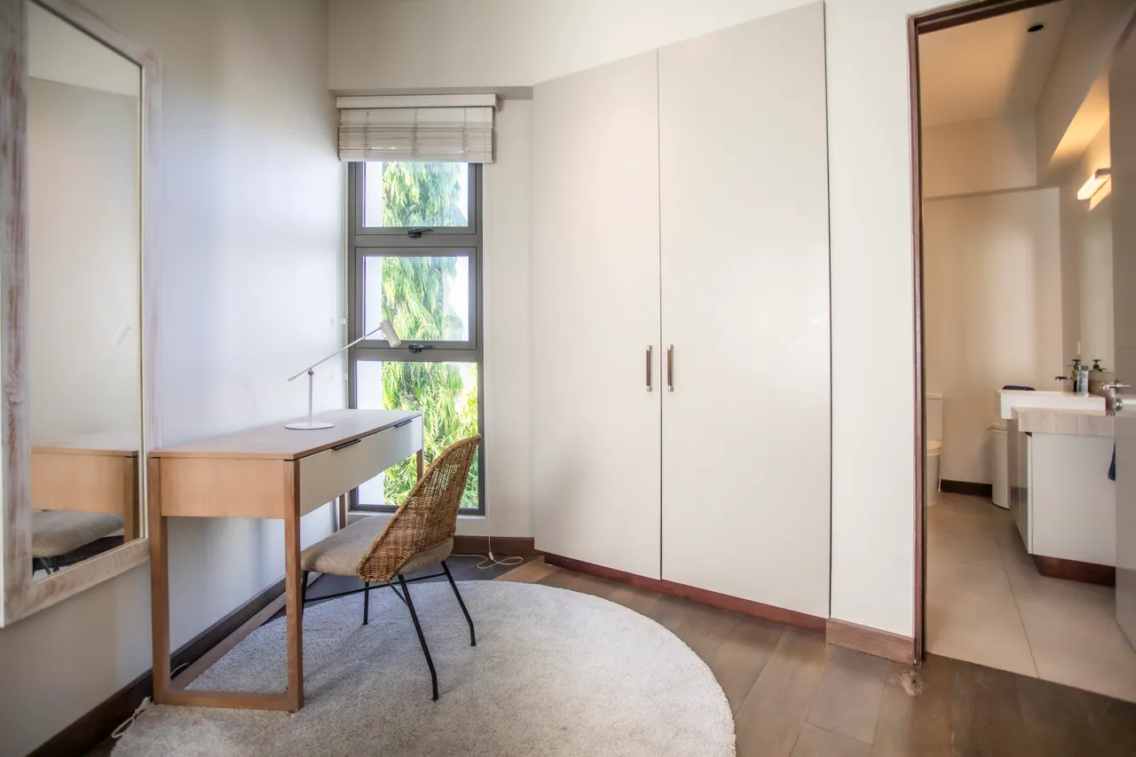 Espace de travail avec bureau en bois et éclairage naturel. Fenêtres offrant une vue dégagée.