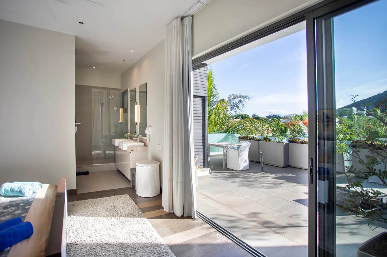 Chambre avec accès à une terrasse et vue sur le jardin. Salle de bain attenante avec deux lavabos.