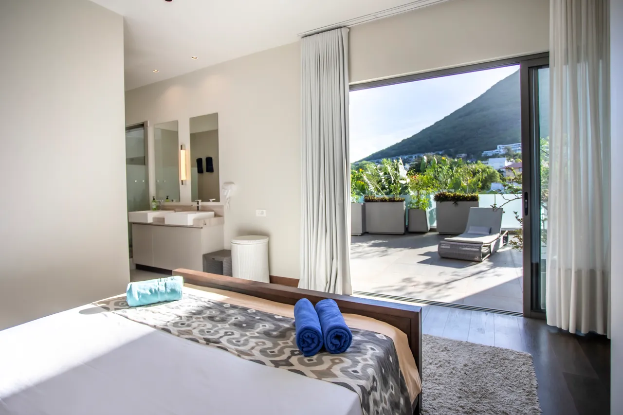Chambre spacieuse avec accès à une terrasse aménagée. Vue sur la montagne environnante.