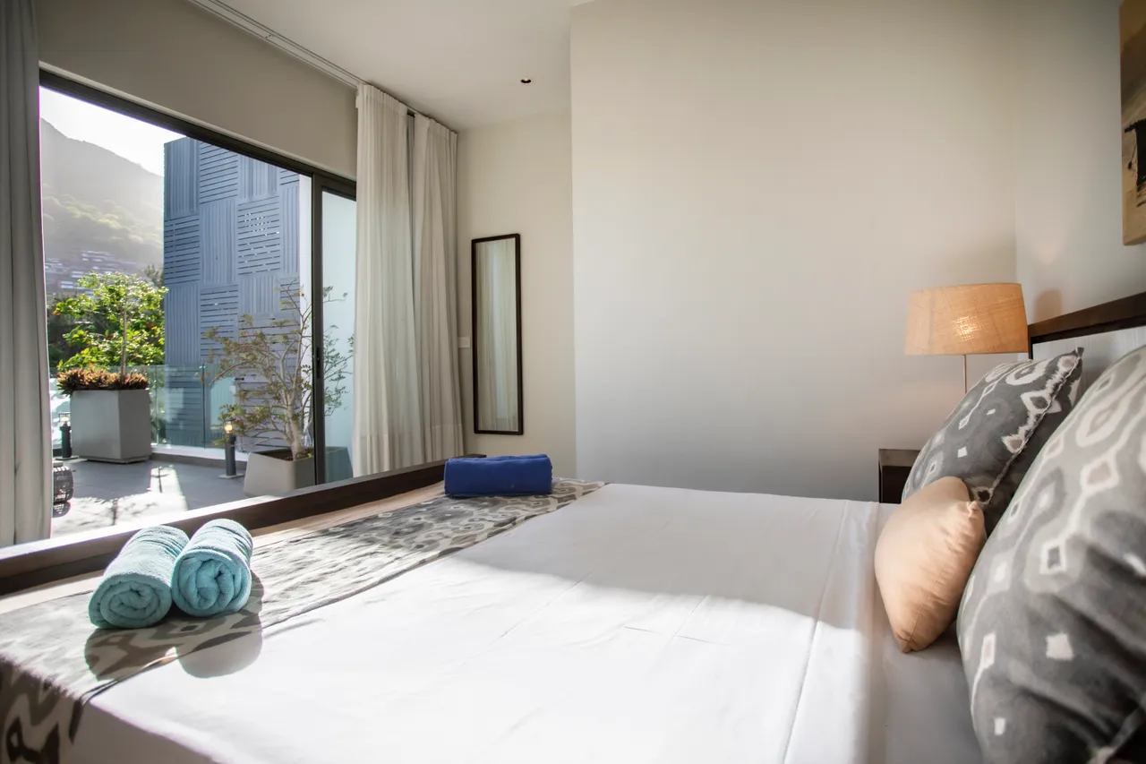 Chambre dotée de grandes fenêtres et vue sur l'extérieur. Lit double et décor simple.