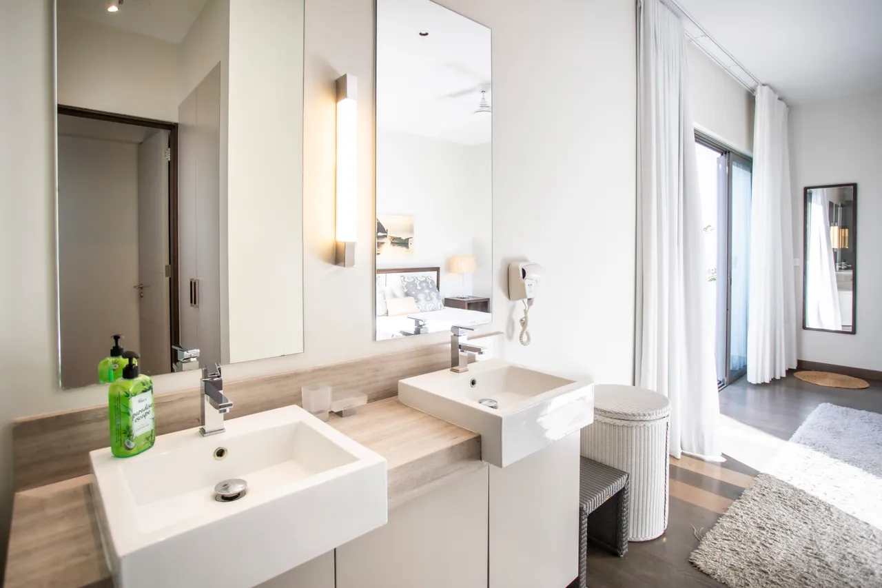 Salle de bain équipée de deux vasques et de rangements intégrés. Accès à une terrasse.