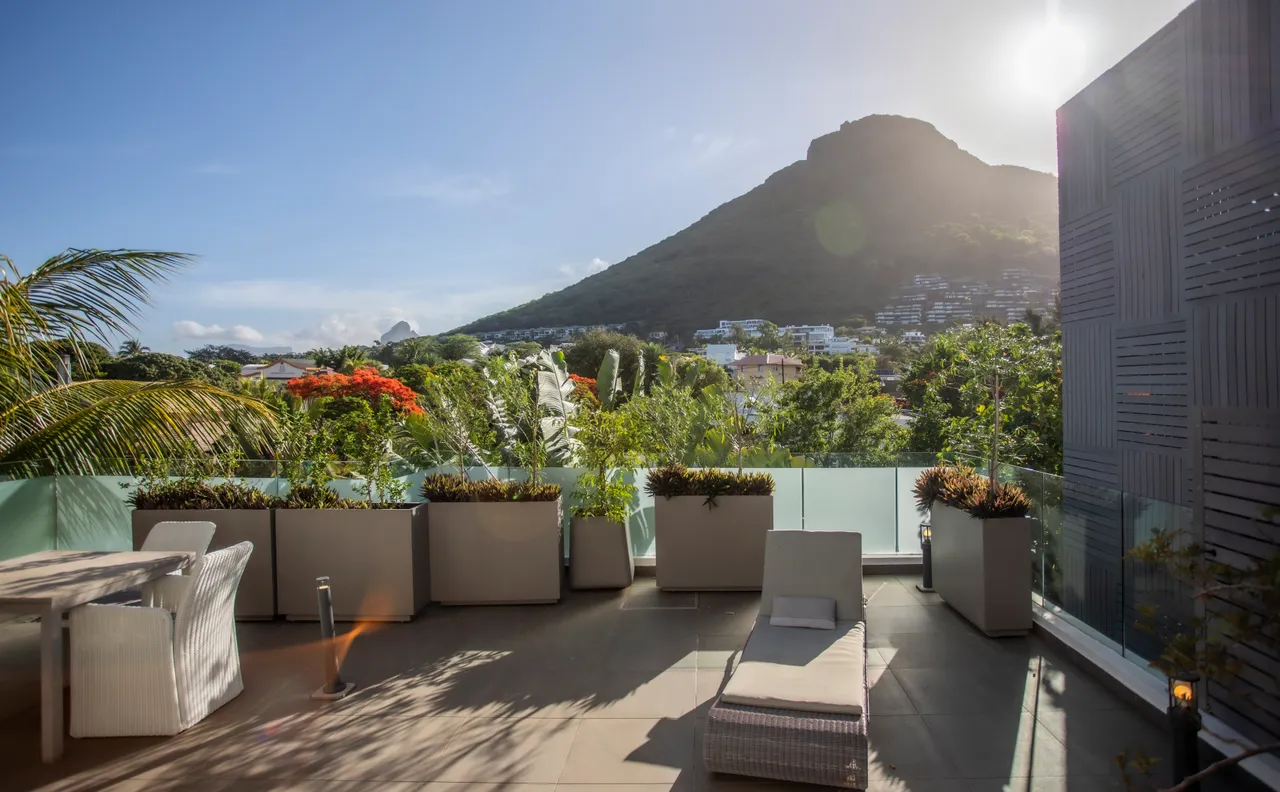 Terrasse avec chaises longues et vue sur la montagne. Espace végétalisé et mobilier moderne.