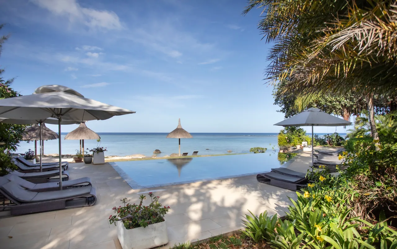 Espace extérieur avec piscine à débordement et transats. Vue sur la mer.