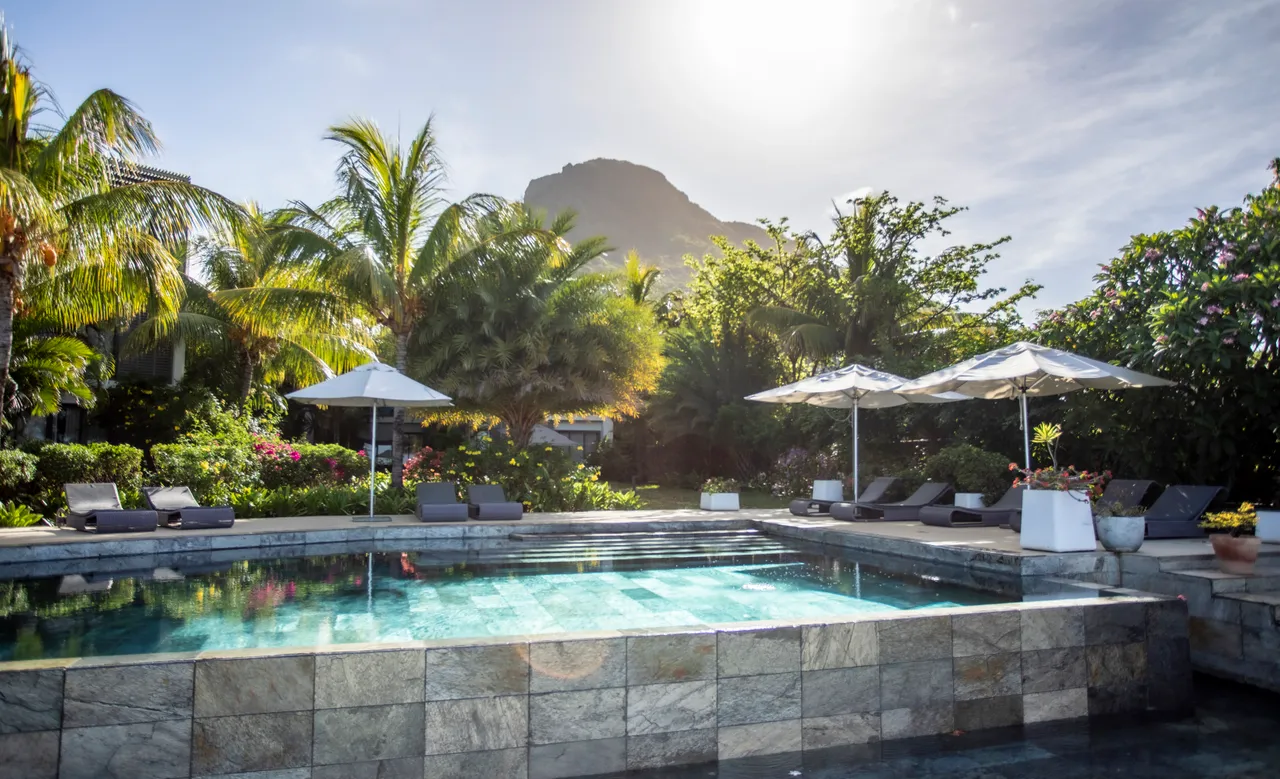 Lumière naturelle se reflétant sur la surface de la piscine. Végétation tropicale environnante.