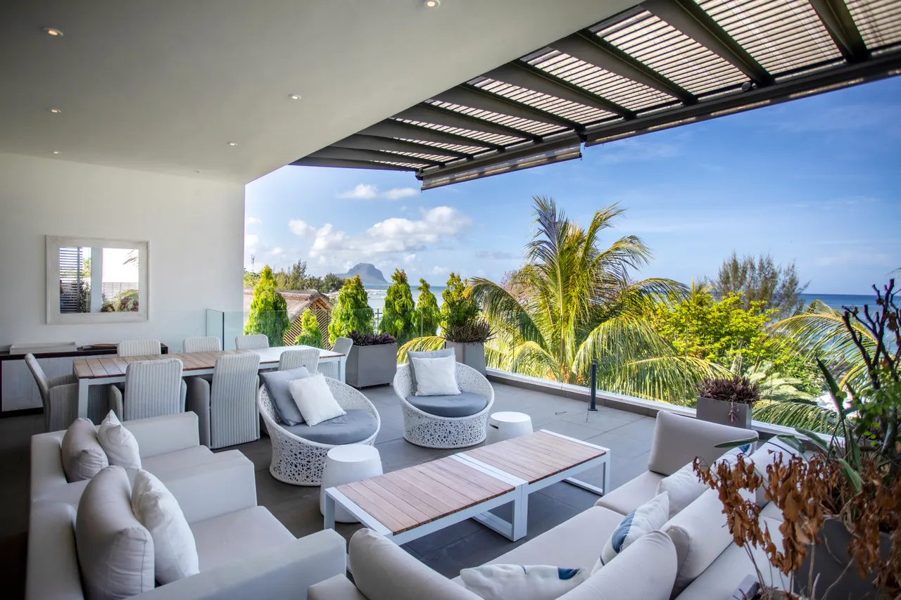 Terrasse avec mobilier en rotin et vue sur la mer. Ombre créée par un auvent.