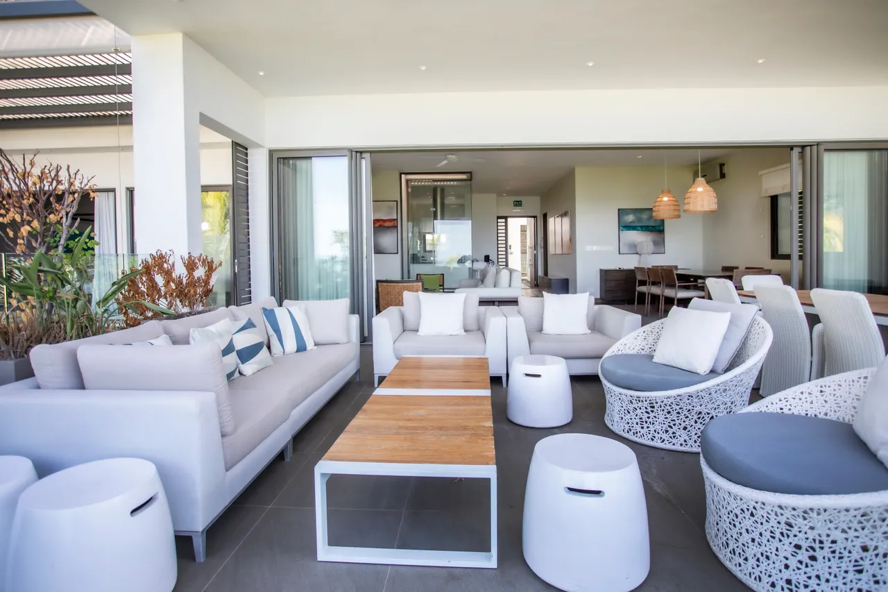 Espace salon ouvert avec de grandes fenêtres et mobilier contemporain. Accès direct à la terrasse.