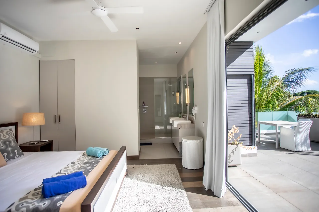 Chambre lumineuse avec accès direct à une terrasse privée. Ventilateur de plafond et mobilier moderne.
