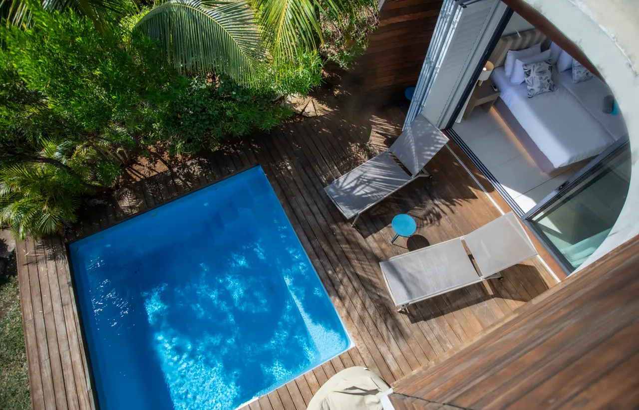 Espace piscine avec chaises longues en bois pour se détendre.  

Vue dégagée sur le jardin luxuriant depuis la terrasse.  

Terrasse en bois intégrée à l'espace piscine pour un accès facile.  

Végétation environnante offrant une ambiance intime autour de la piscine.  

Coin salon à proximité de la piscine, idéal pour se relaxer.
