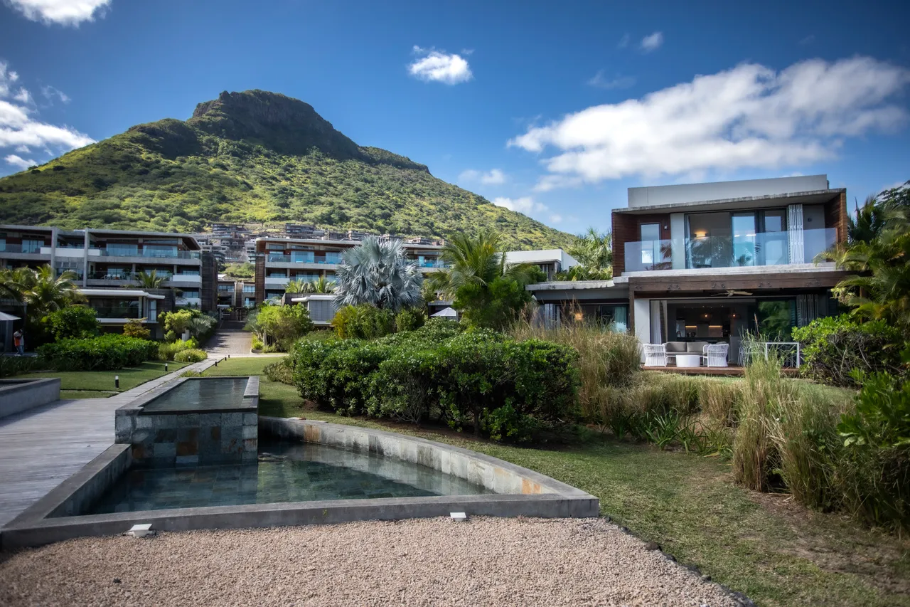 Vue dégagée sur la montagne depuis l'espace extérieur.  

Jardin paysager entourant la villa avec divers plants tropicaux.  

Terrasse en bois offrant un accès facile à l'espace de vie.  

Piscine d'angle intégrée au paysage pour une atmosphère relaxante.  

Mobilier moderne sur la terrasse pour des moments de détente.