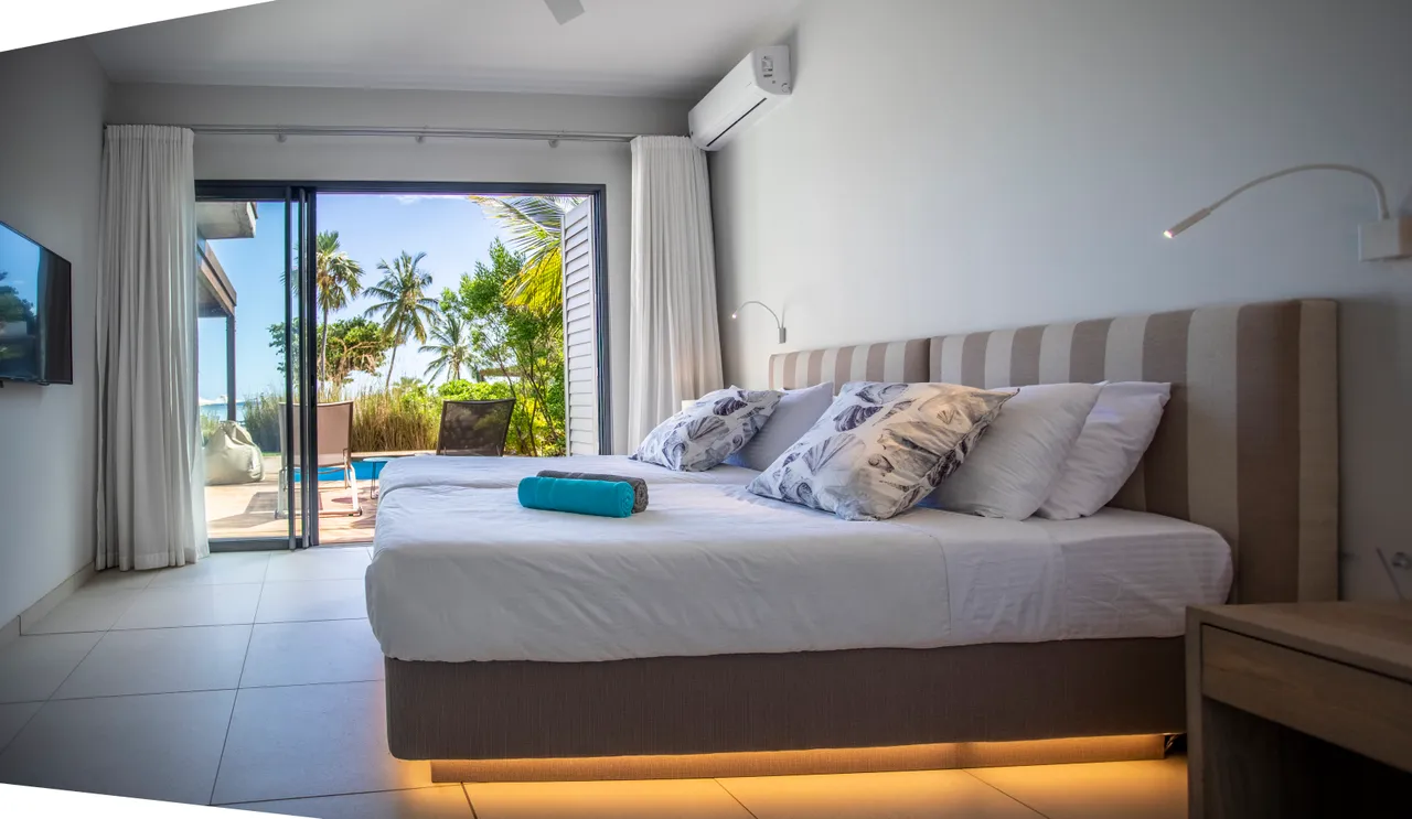 Chambre avec lit double et accès direct à la terrasse.  

Fenêtres laissant entrer la lumière naturelle et vue sur le jardin.  

Mobilier simple avec éclairage doux au bord du lit.  

Espace de rangement intégré à proximité pour plus de praticité.  

Couleurs neutres créant une ambiance apaisante à l'intérieur.