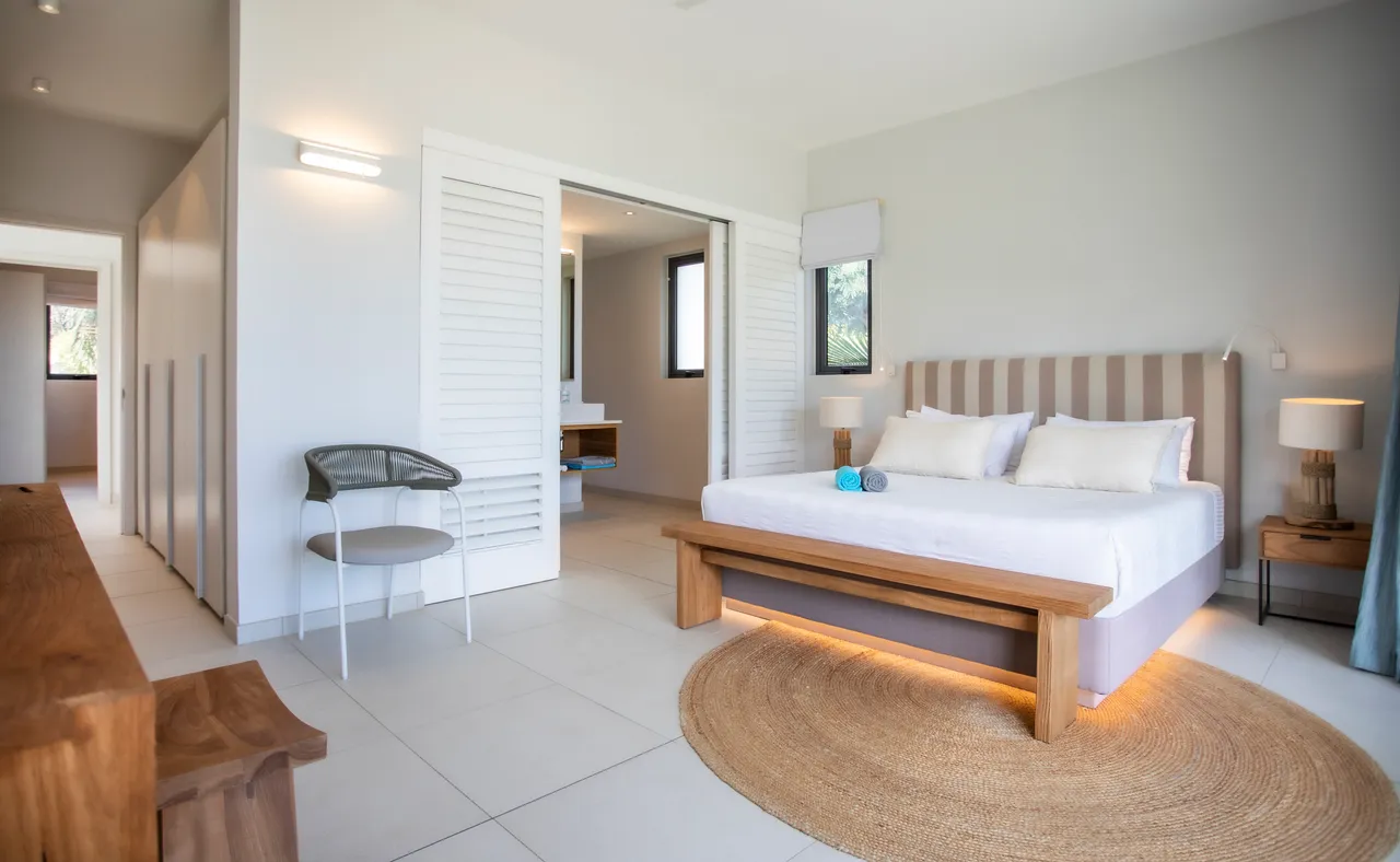 Chambre avec lit double et rangement intégré dans le mur.  

Fenêtres offrant une vue sur l'extérieur et une bonne luminosité.  

Éclairage indirect mettant en valeur les éléments en bois.  

Sol carrelé facile à nettoyer et à entretenir.  

Espace de travail aménagé avec une chaise design fonctionnelle.