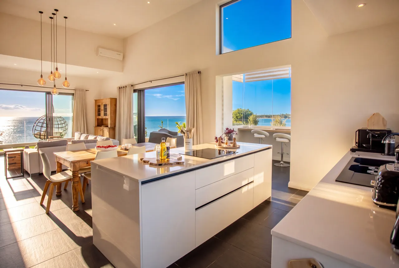 Espace ouvert avec cuisine moderne et vue sur la mer. Bar au comptoir pour des repas décontractés.