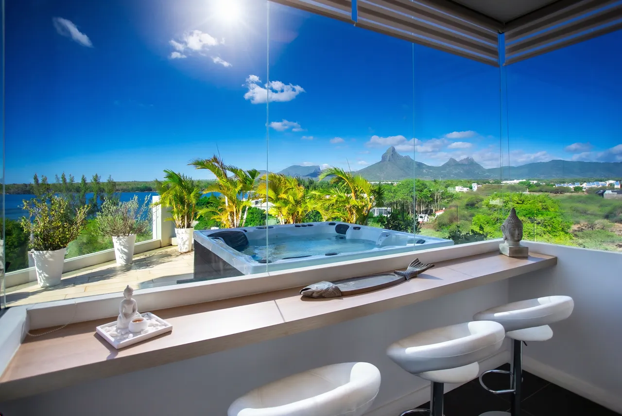Espace extérieur avec jacuzzi et vue dégagée sur la mer. Bar intégré pour se détendre.
