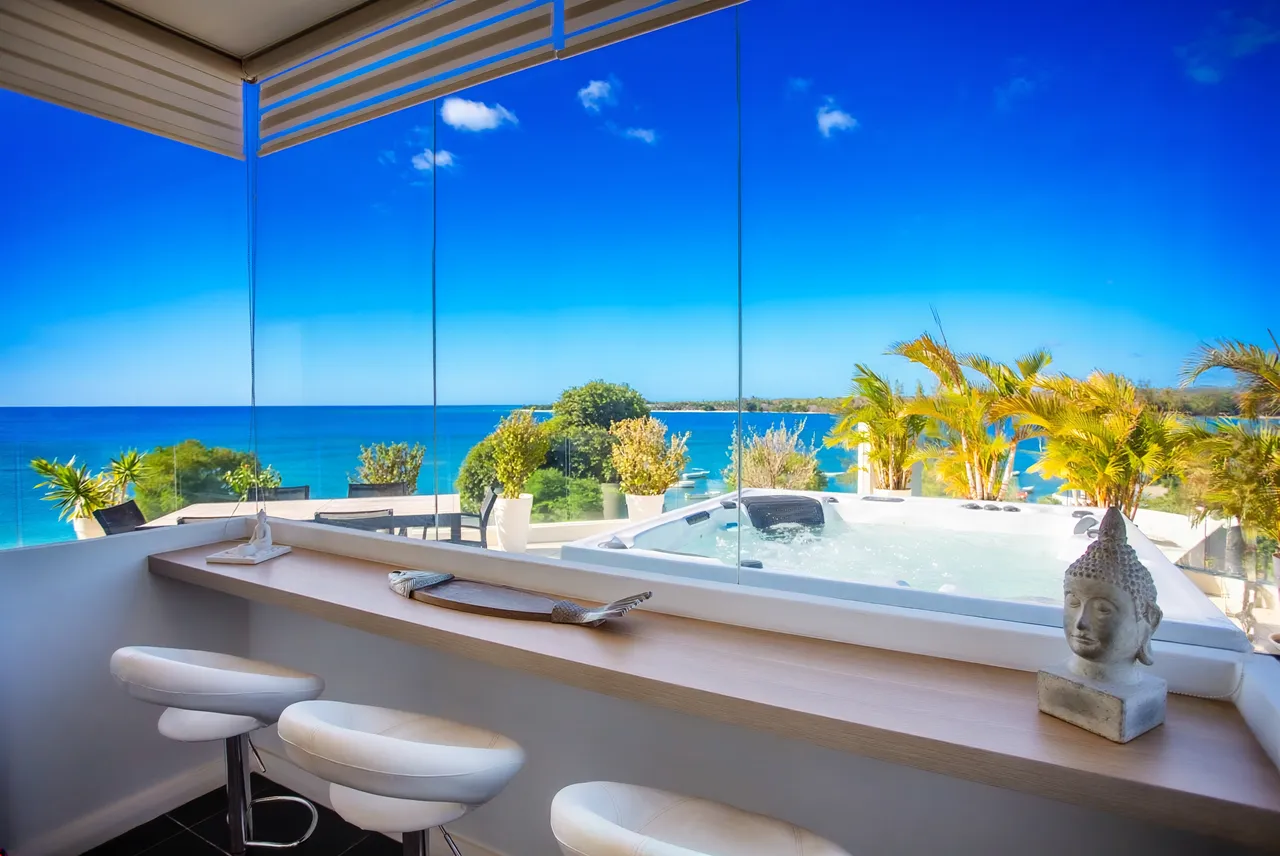 Espace bar avec tabourets et vue sur le jacuzzi et la mer.