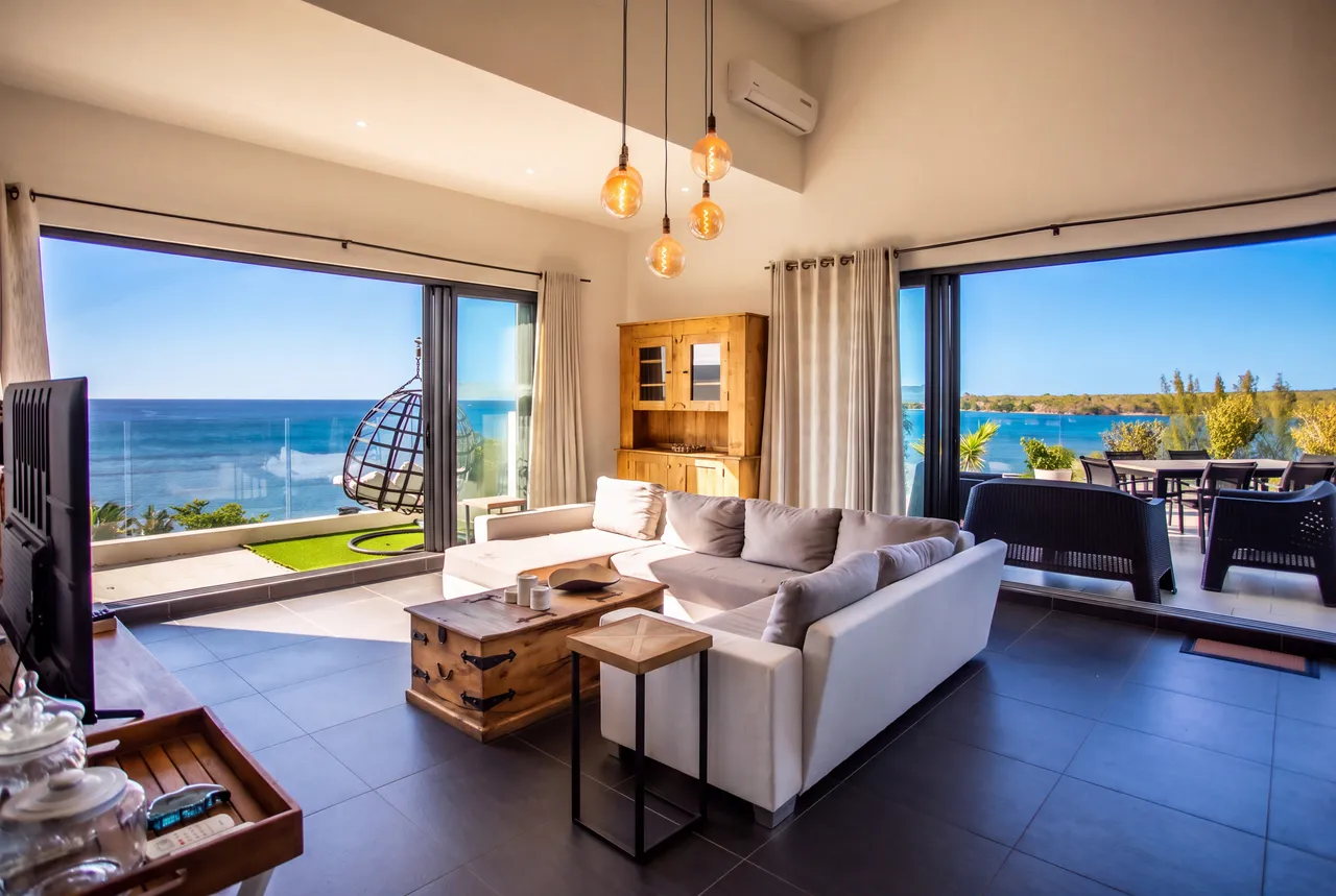 Vue dégagée sur la mer depuis le salon, avec un coin détente suspendu. Espace lumineux équipé d'un mobilier contemporain et de grandes baies vitrées.