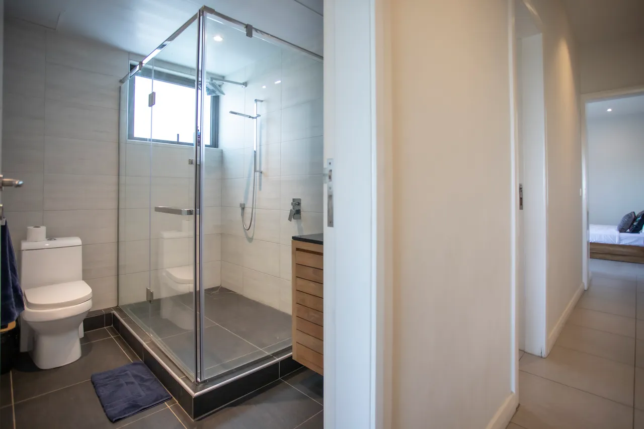 Salle de bain contemporaine avec douche en verre et meuble en bois. Éclairage naturel par une fenêtre.