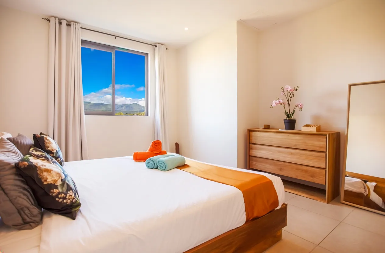 Chambre avec un grand lit et rangement en bois. Fenêtre offrant une vue sur les montagnes.