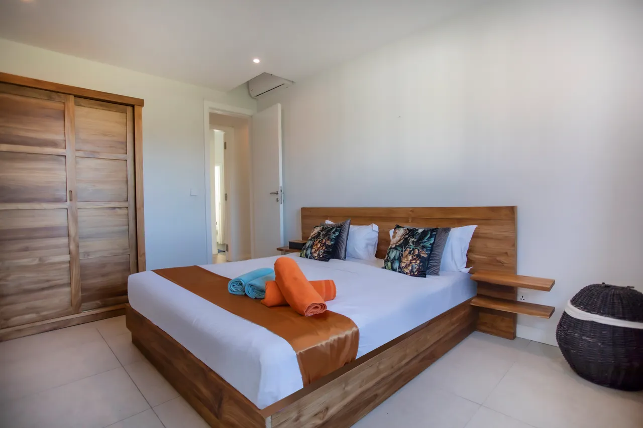Chambre avec un lit double et rangement en bois clair. Éclairage naturel par une fenêtre.