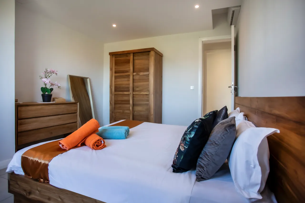 Chambre lumineuse avec un lit double et rangements en bois. Fenêtre offrant une vue sur l'extérieur.
