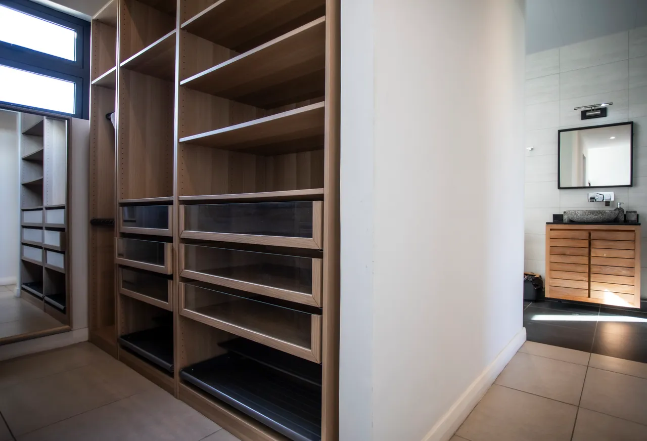 Rangement en bois clair avec tiroirs intégrés et miroir. Éclairage naturel provenant d'une fenêtre.