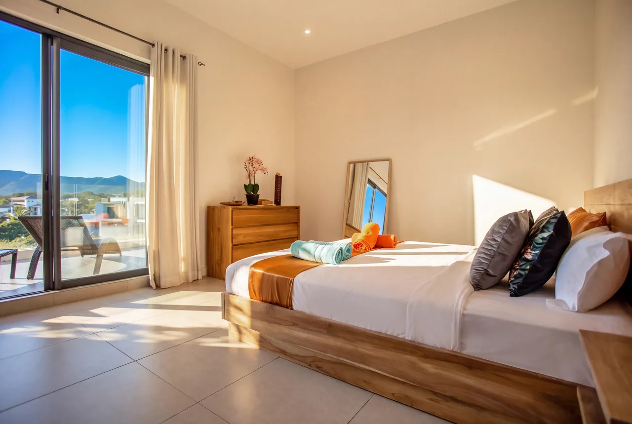 Chambre avec un lit double en bois et rangement. Accès à un balcon avec vue.